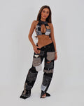 A model posing in a studio setting wearing a matching two-piece patchwork outfit consisting of a halter crop top and distressed patchwork pants.